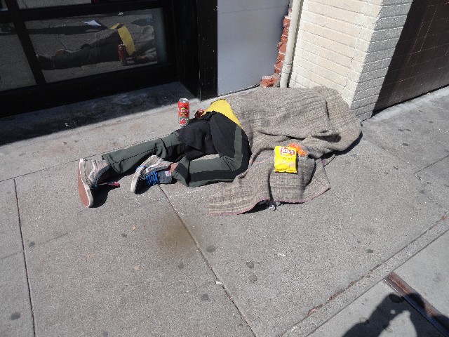 Person laying on sidewalk with potato chips and peanut butter cheese crackers