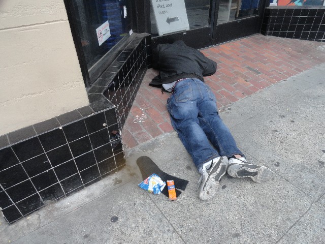 Homeless person on sidewalk with chips and crackers delvered by The Little Way Homeless Outreach